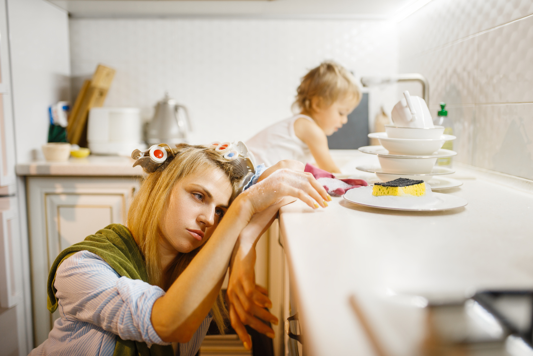 Little Girl Washing Dishes near Tired Housewife